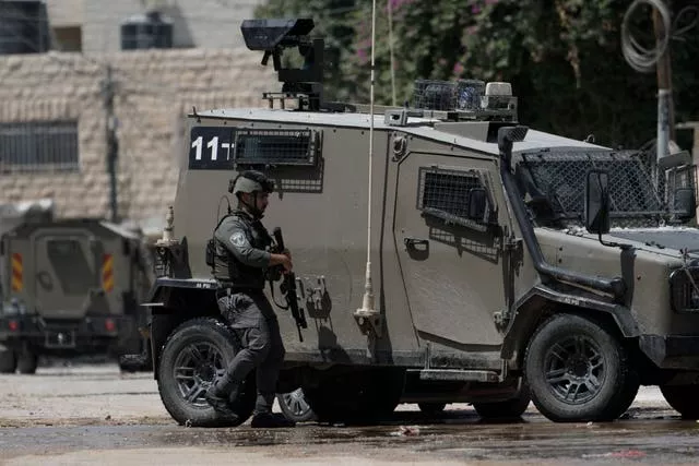 A member of the Israeli forces walks next to an armoured vehicle