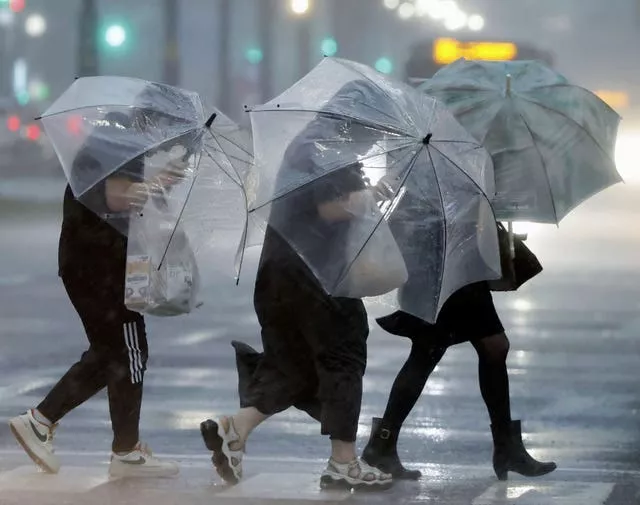 People holding umbrellas struggle with the heavy rain in Kagoshima, western Japan