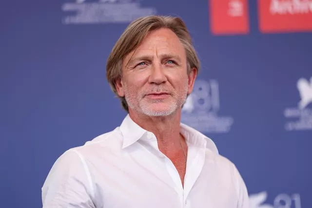 Daniel Craig, in a white shirt, poses for photographers at the Venice Film Festival