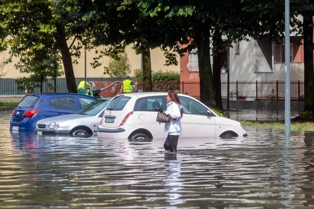 A woman wades through floodwater in Milan