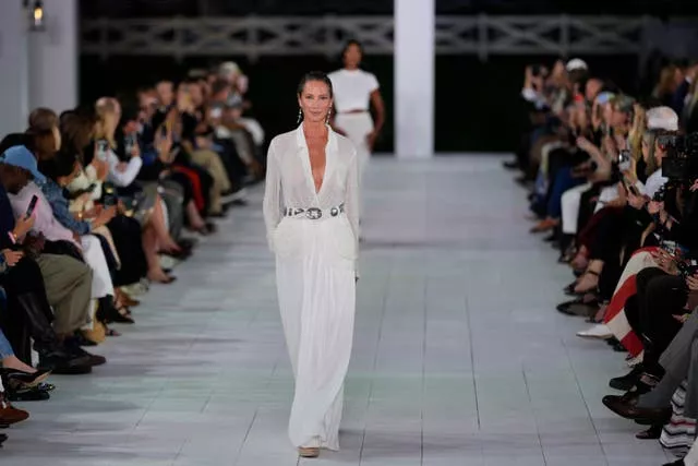 Christy Turlington walks down runway in plunging white V neck shirt and flared trousers