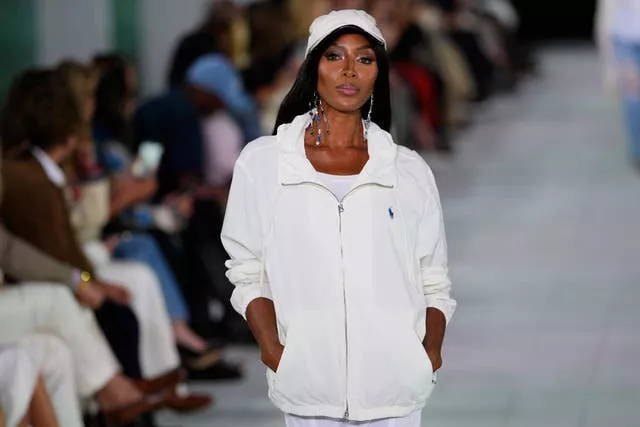 Naomi walks down runway in white baseball cap and bomber jacket