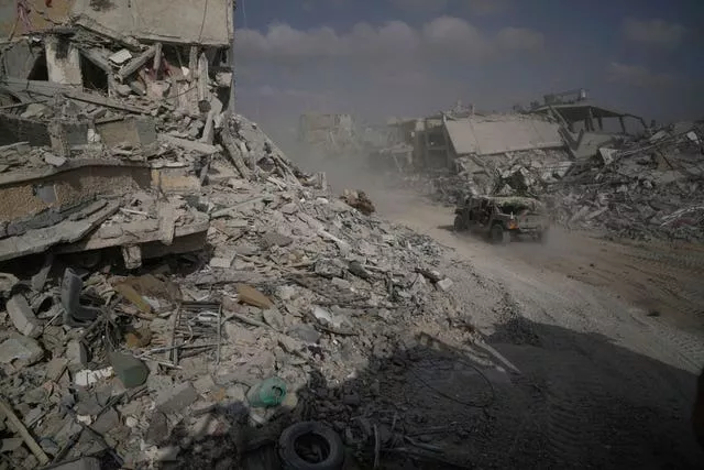 Israeli soldiers drive near destroyed buildings during a ground operation in the Gaza Strip