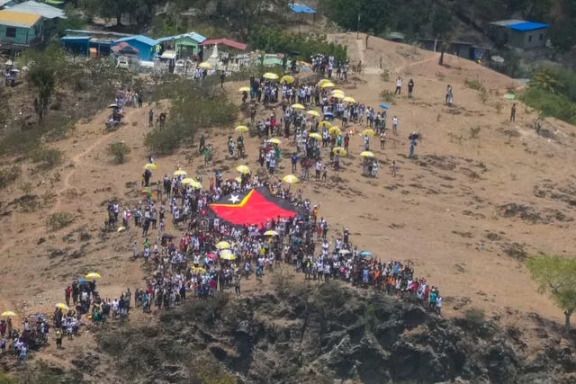 People display a East Timor national flag to show it to Pope Francis taking off with his flight from Díli, East Timor and bound to Singapore