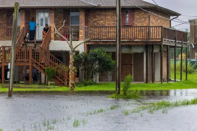 Residents sit on their front porch as they watch water rise