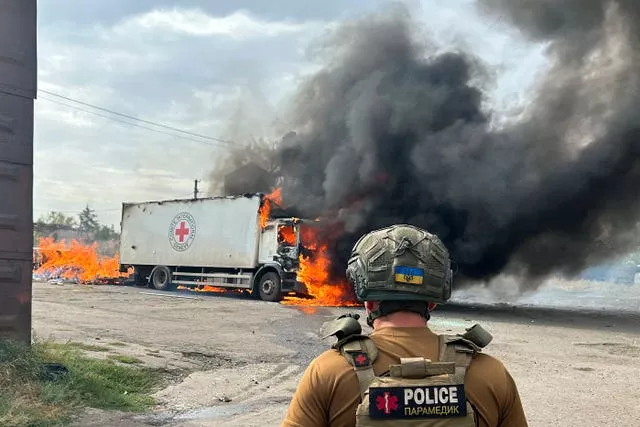 A police officer looking at a burning Red Cross vehicle that was destroyed in a Russian strike in the Donetsk region