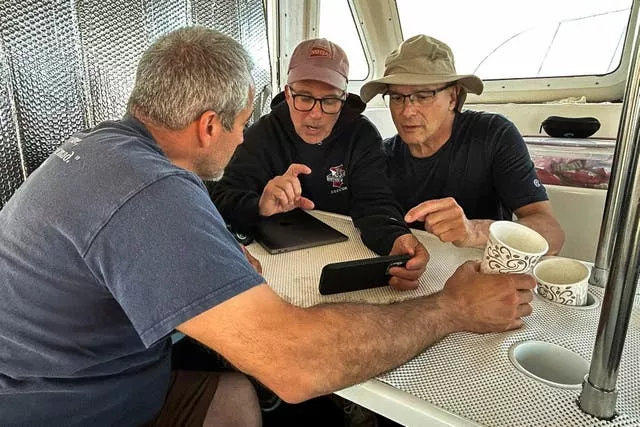 Three people around a table review footage between dives on the passenger steamship Le Lyonnais