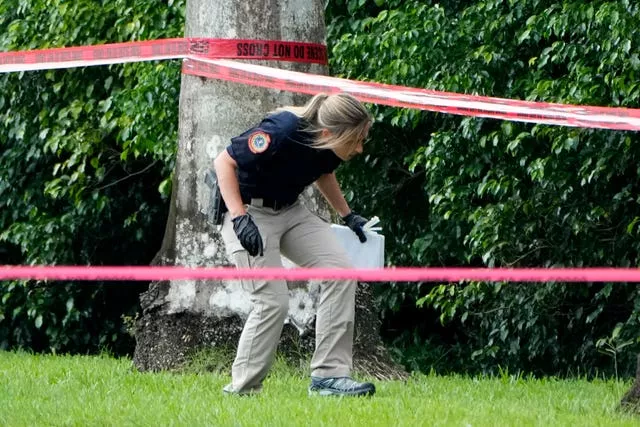 A police official works next to a hedge outside the Trump International Golf Club