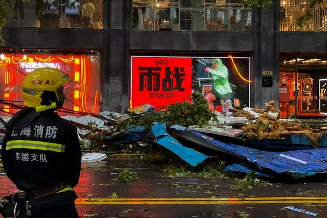 A firefighter stands near debris on a business street in Shanghai, China, in the aftermath of Typhoon Bebinca 