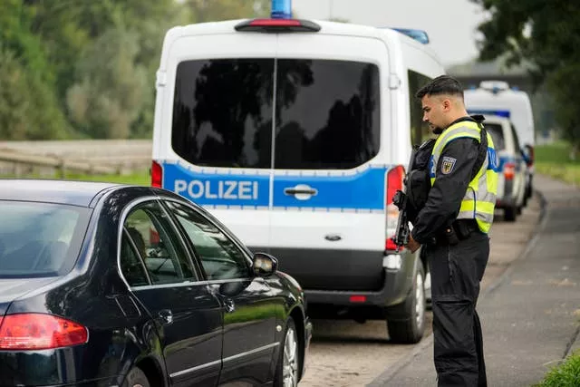 An armed German police officer checks the details of a French car near the border to Belgium in Aachen, Germany