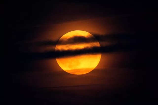 The moon rises through clouds over the Atlantic Ocean off the coast of Camden, Maine