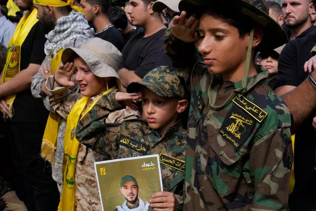 Boys salute during the funeral procession of Hezbollah members