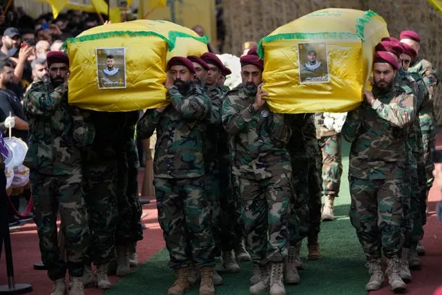 Hezbollah members carry the coffins of two of their comrades during a funeral procession