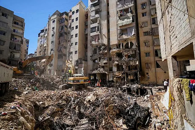 Emergency workers use excavators to clear the rubble at the site of Friday’s Israeli strike in Beirut’s southern suburbs