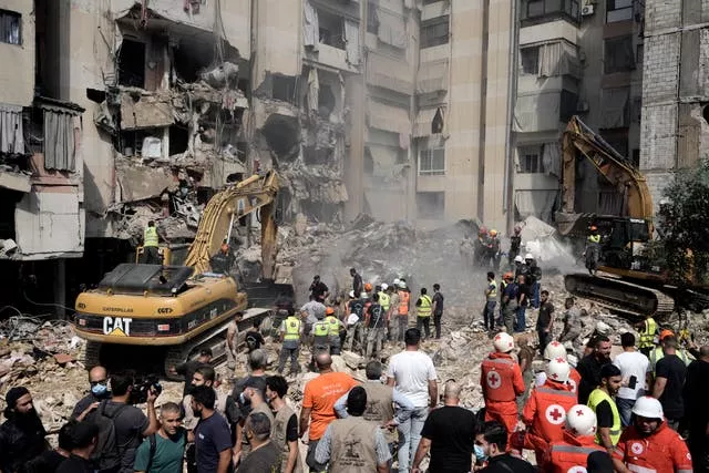 Excavator clearing rubble from destroyed building