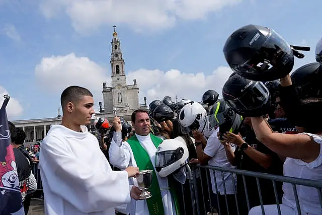 A priest holding a police motorcycling helmet, blesses the helmets of faithful during the IX Pilgrimage of the Blessing of Helmets that draws tens of thousands at the Roman Catholic holy shrine of Fatima, in Fatima, Portugal