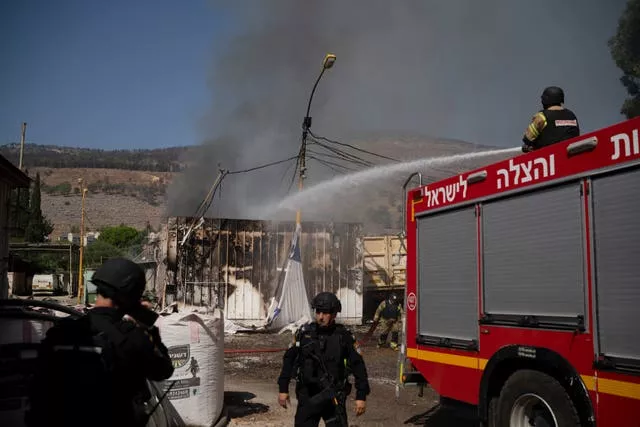 Firefighters work to extinguish a fire after a rocket hit a local municipality storage in Kiryat Shmona, northern Israel