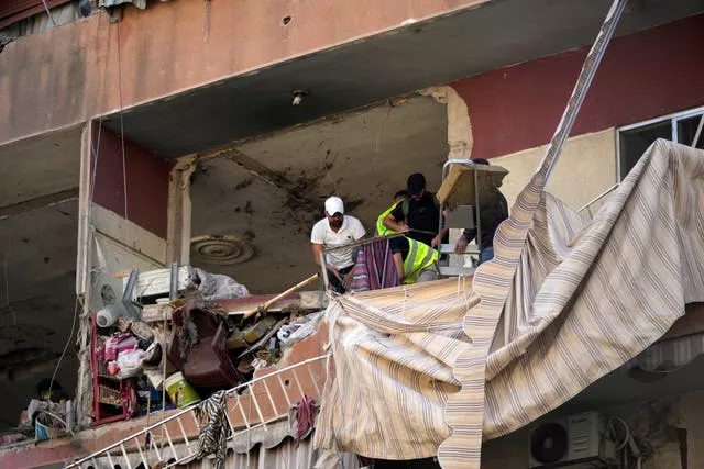 Residents and rescuers check a building that was hit by an Israeli airstrike in Beirut’s southern suburbs 