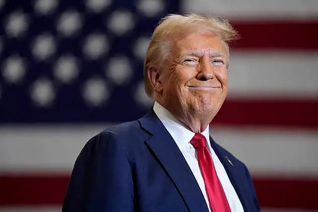 Donald Trump smiling in front of a US flag