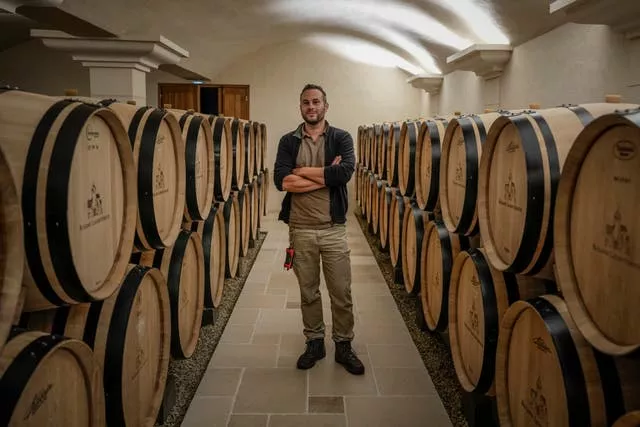 Arnaud Lavantureux standing between rows of wine barrels