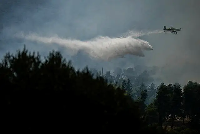 An Israeli firefighters' plane uses a fire retardant to extinguish a fire after a rocket fired from Lebanon hit an open area near the city of Safed, northern Israel