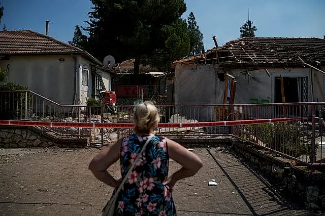 A woman looks at a damaged house that was hit by a rocket fired from Lebanon, near Safed, northern Israel