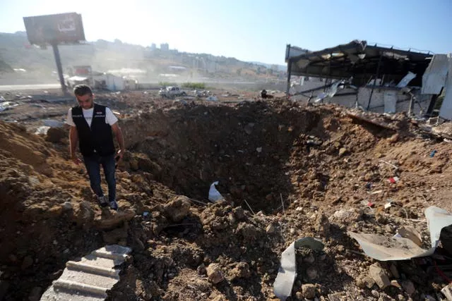 A police officer next to a bomb crater in Lebanon