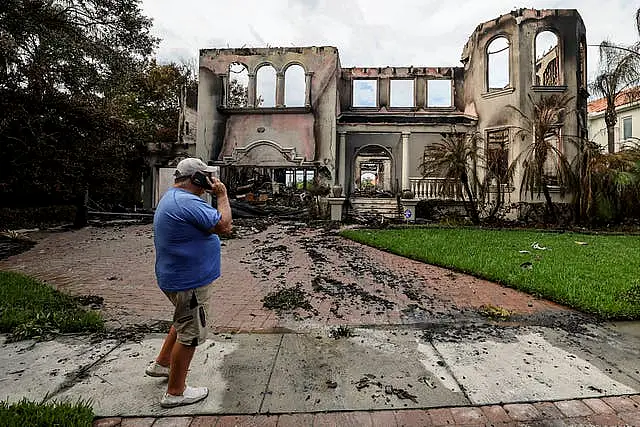 Joe Daum looks at the remains of a friend’s home that burned during Hurricane Helene on Davis Island, Tampa, Florida