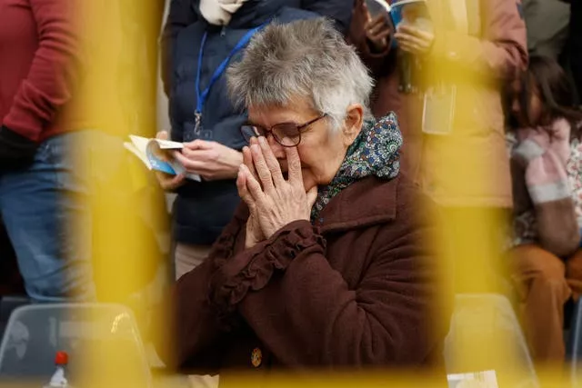 A woman prays in a crowd