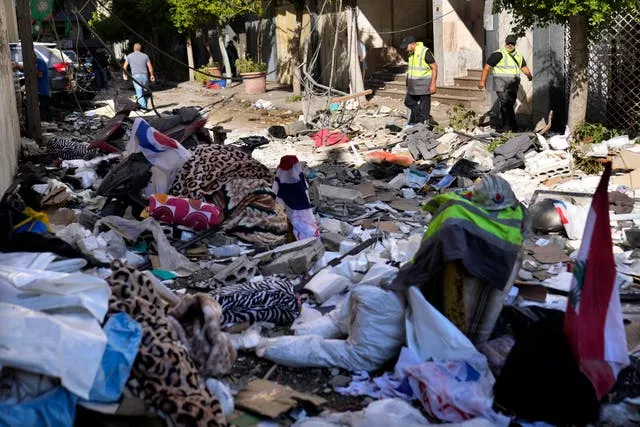 Hezbollah paramedics walk among debris after an airstrike in Beirut