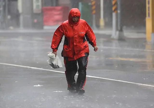 A person struggles in the wind and rain on a street