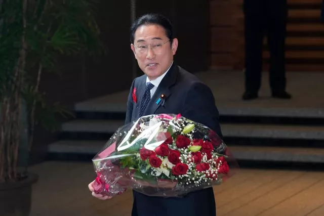 Japan’s outgoing prime minister Fumio Kishida holding a bouquet of flowers