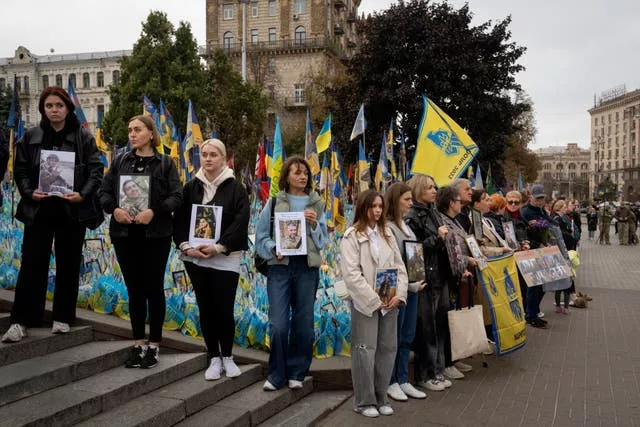 People hold photos of their relatives during a nationwide minute of silence in memory of fallen soldiers 