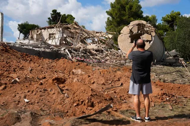 A man takes photos of a destroyed building