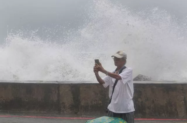 A man takes a selfie with waves hitting the shore of Kaohsiung