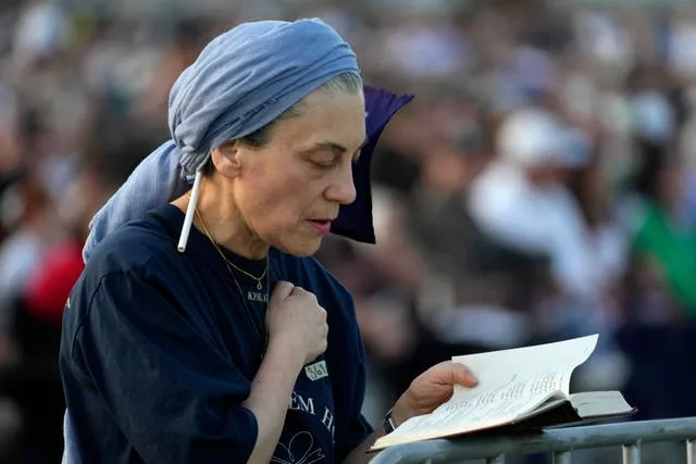 A woman prays as members of the Jewish community gather at a park in Sydney, Australia