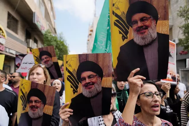 Palestinian activists hold posters with pictures of late Hezbollah leader Hassan Nasrallah during a protest marking the one year anniversary of the Israel Hamas war