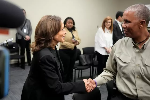 Kamala Harris shakes hands with a man in a grey shirt