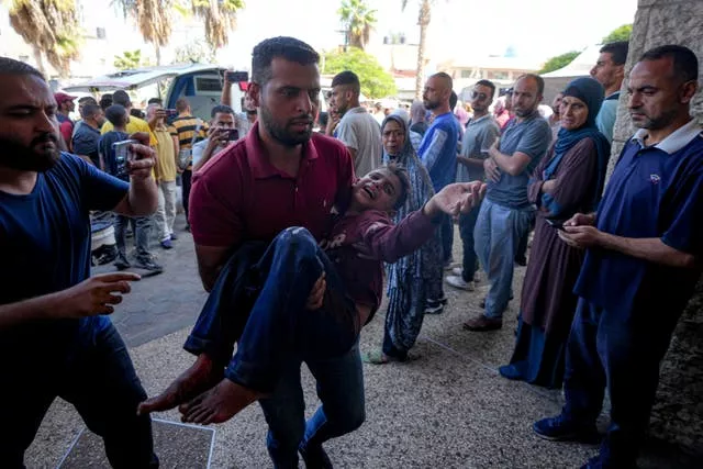 A Palestinian man carries an injured child after the Israeli air strike in Deir al Balah