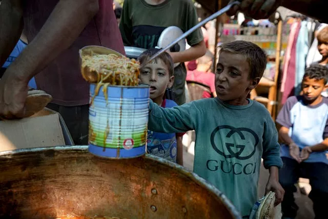 A displaced child lines up for food distribution in Deir al-Balah, Gaza Strip