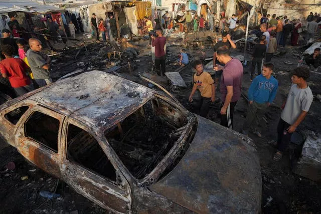 Palestinians look at the damage after an Israeli strike hit a tent area in the courtyard of Al Aqsa Martyrs hospital in Deir al Balah, Gaza Strip