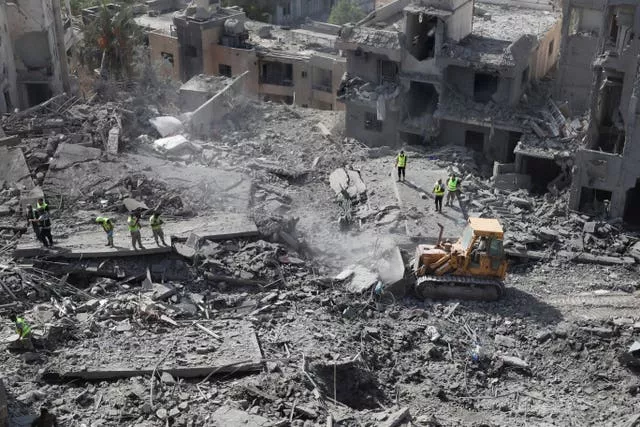 Rescue workers use a bulldozer to remove the rubble of destroyed buildings at the site that was hit by Israeli air strikes in Qana 