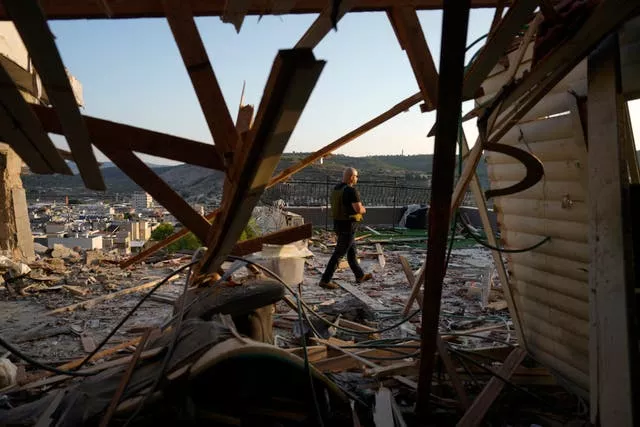 Israeli security forces survey damage to a home in the north of the country which was struck by a rocket fired from Lebanon