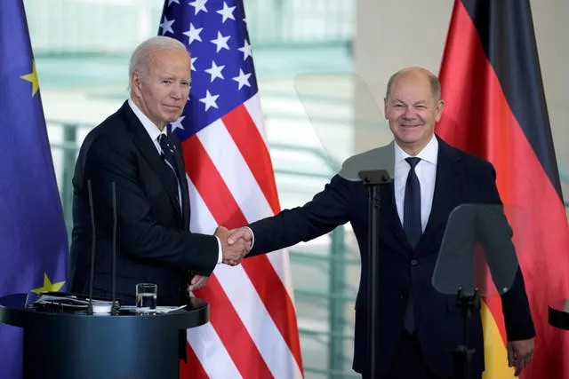 US President Joe Biden and German Chancellor Olaf Scholz shaking hands in front of US and German flags