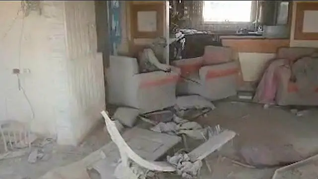 A man in an armchair in a heavily damaged house