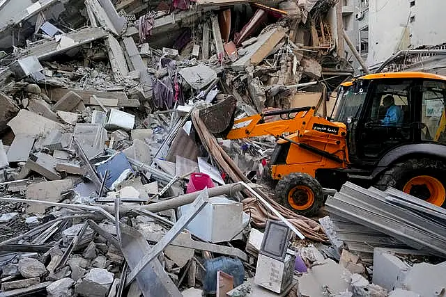 Rescue workers use a bulldozer to remove rubble of destroyed buildings at the site of an Israeli air strike