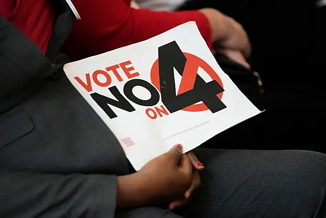 A person in the audience holds a sign against Amendment 4 