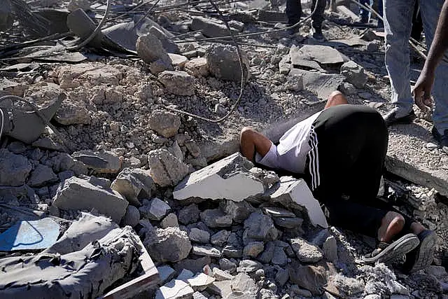 A man searches for his missing relative under the rubble of a destroyed building, at a popular neighbourhood that was hit Monday night by Israeli air strikes