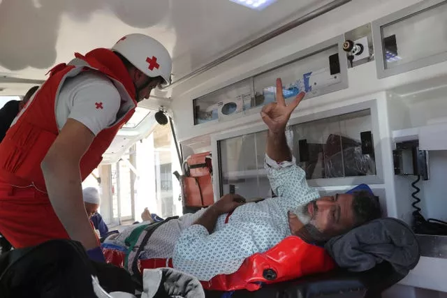 An injured cameraman flashes victory sign as he moved by the Lebanese Red Cross