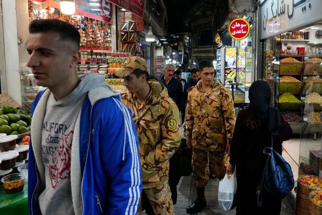 Two army soldiers and people walk through Tajrish traditional bazaar in northern Tehra